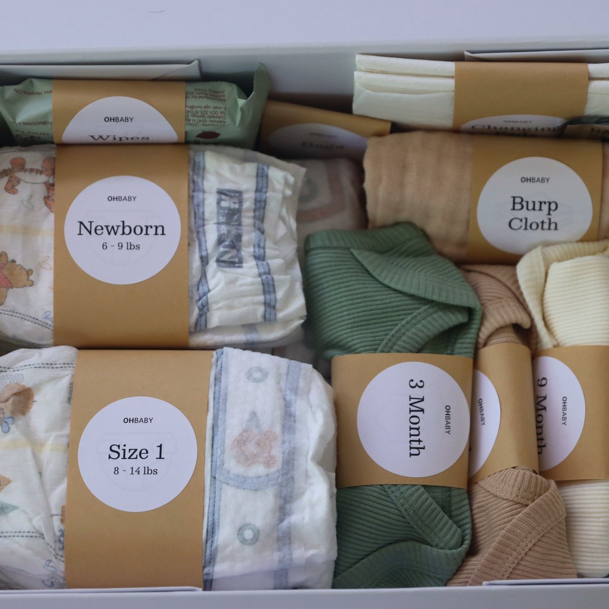 Close-up of Oh Baby Kit labeled diapers and bodysuits.