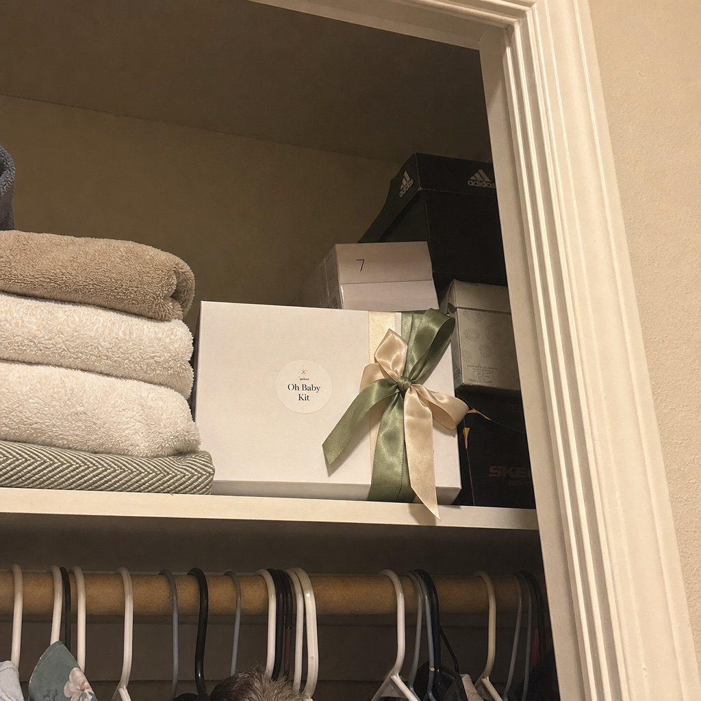 Oh Baby Kit box stored on a closet shelf next to folded towels.