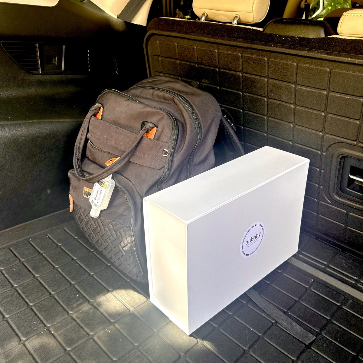Oh Baby Kit box stored in a car cargo area beside a backpack.