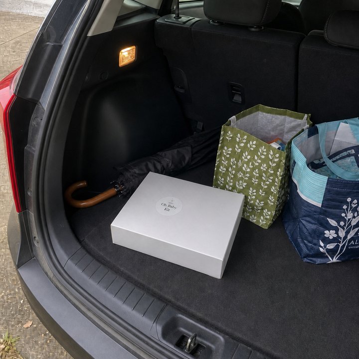 Oh Baby Kit box tucked in a car trunk beside grocery bags.